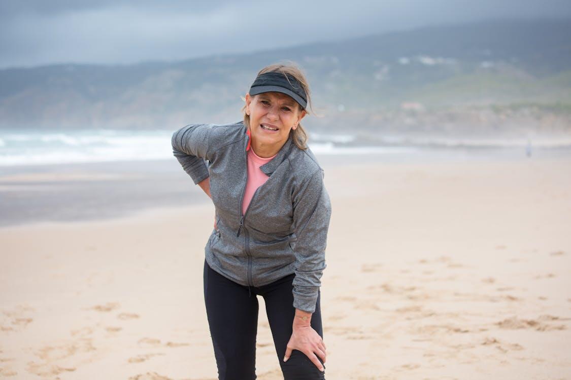 Woman holding lower back on beach