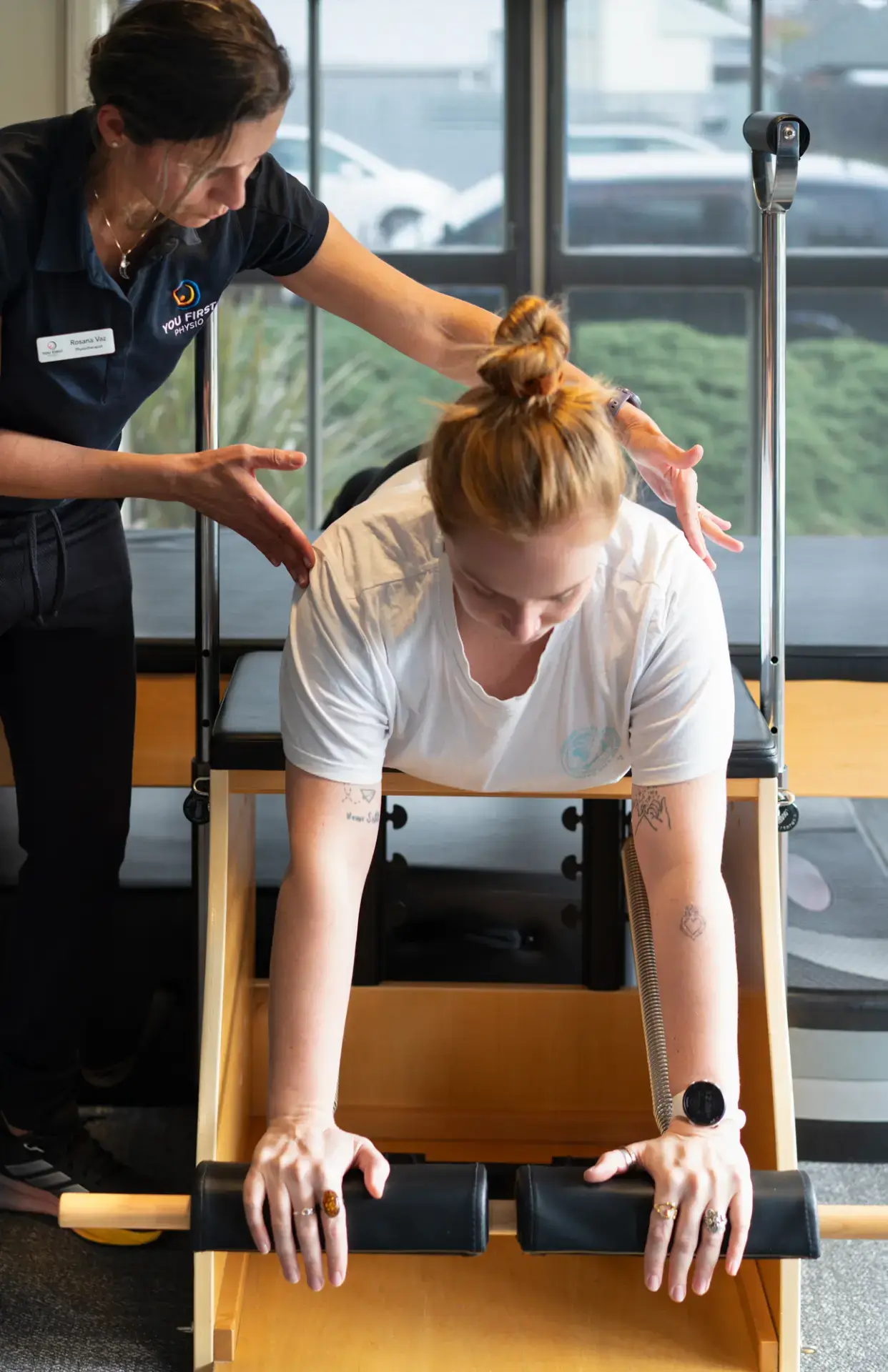 Physiotherapist guiding woman on Pilates reformer machine
