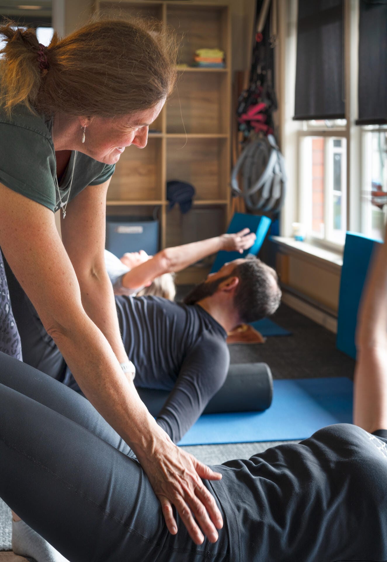 Instructor assisting client with floor stretch exercise