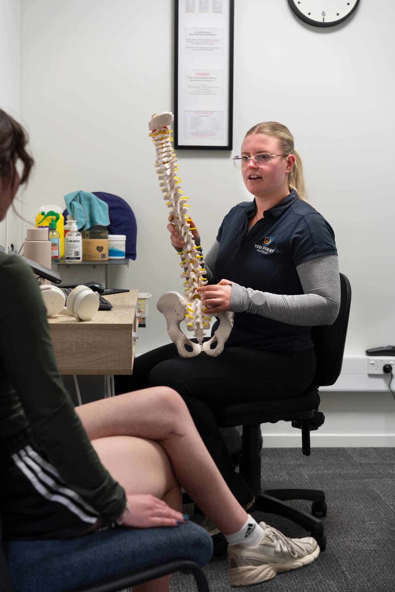 Physiotherapist explaining spine model to patient