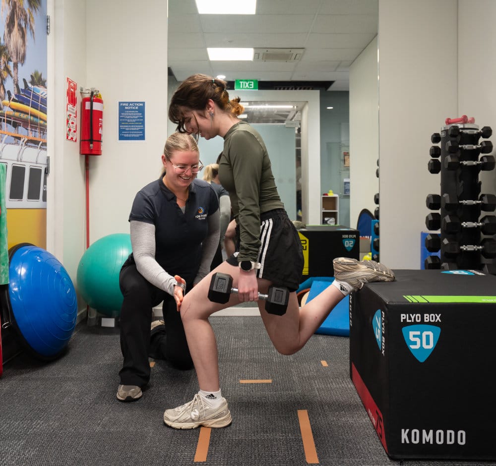 Trainer assisting woman with Bulgarian split squat