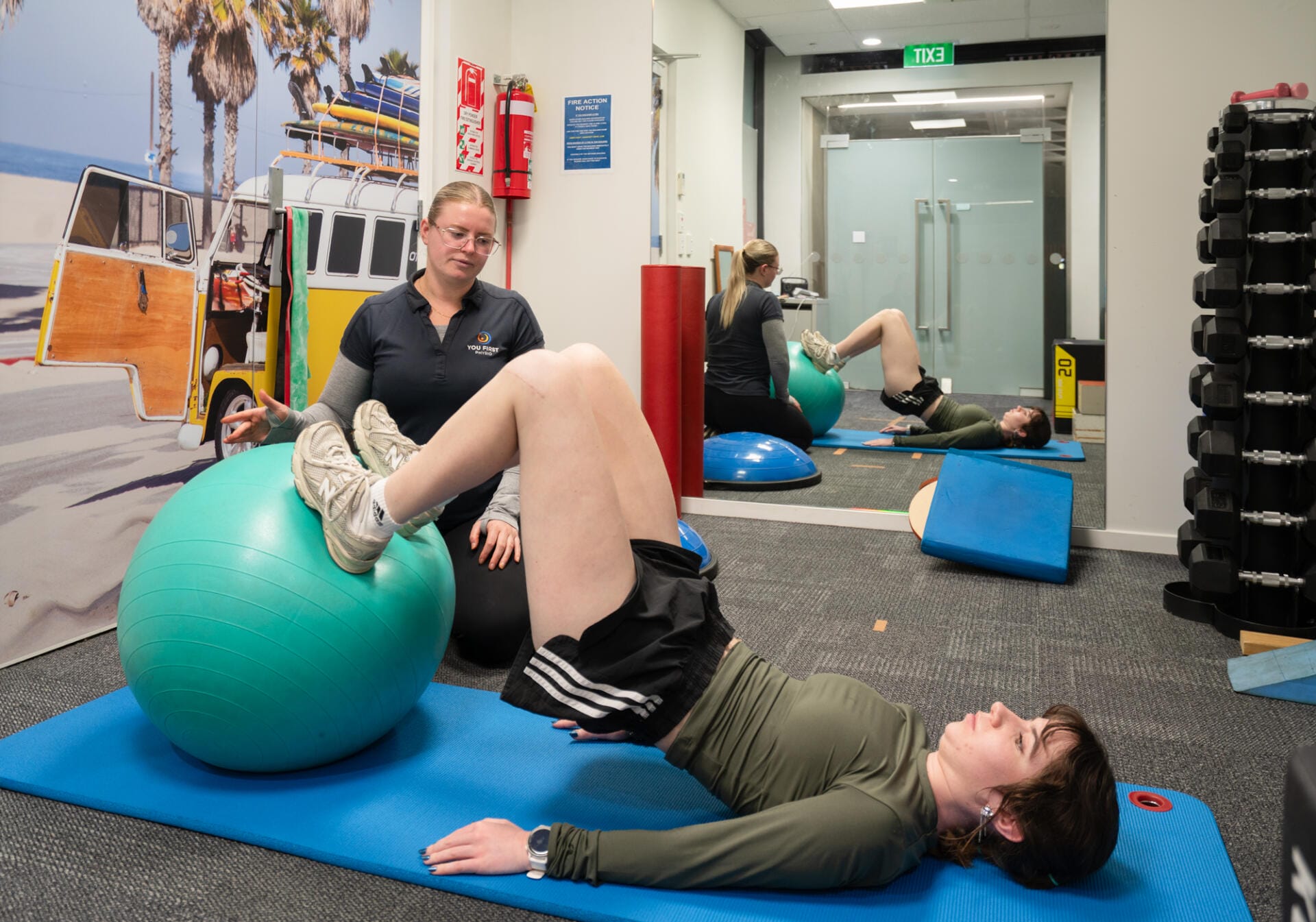 Physiotherapist guiding woman with stability ball exercise