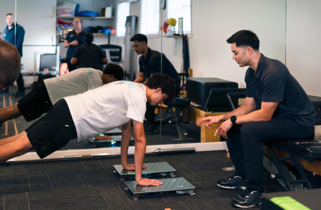 Trainer supervising client doing push-up assessment indoors