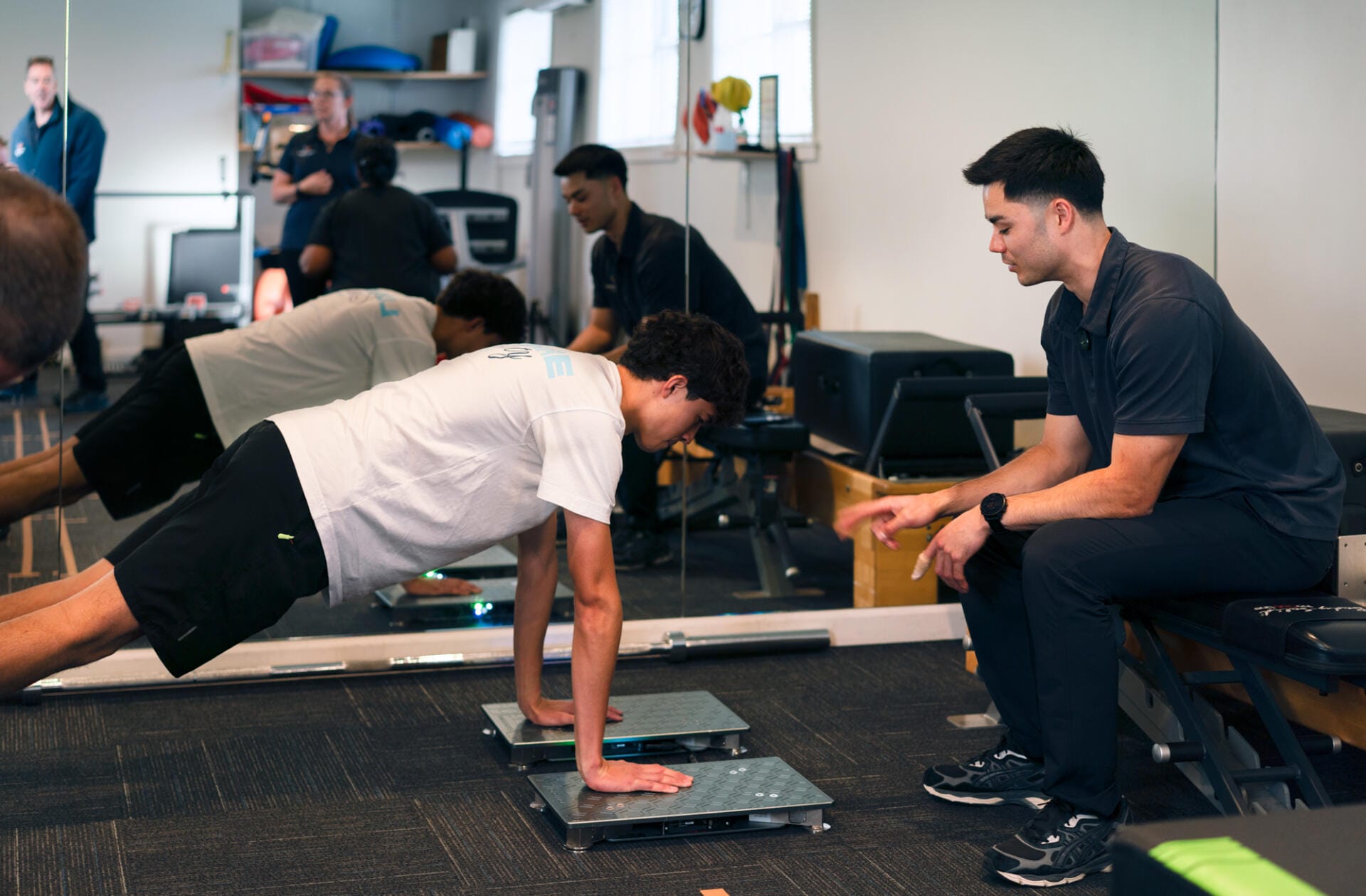 Trainer supervising client doing push-up assessment indoors
