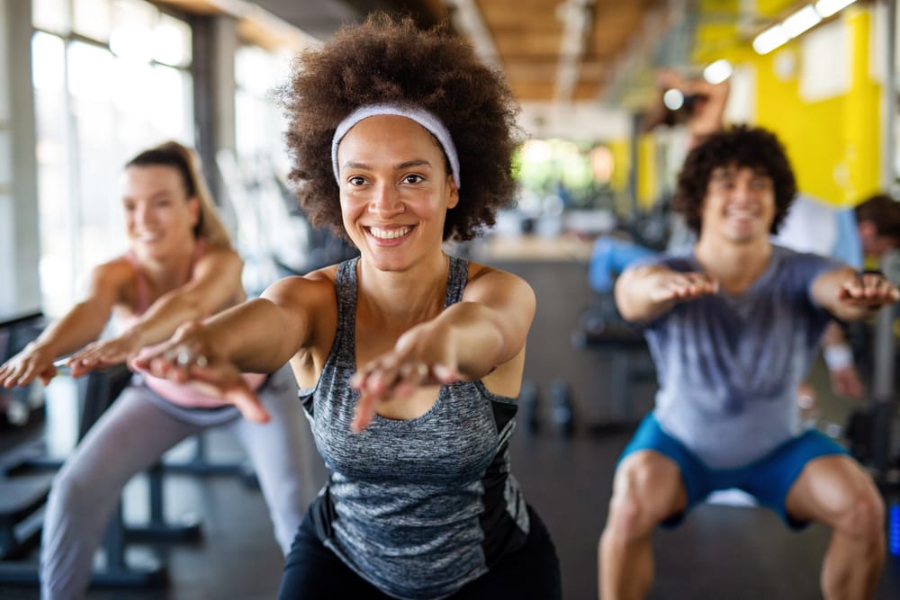 Group of friends doing squats in gym
