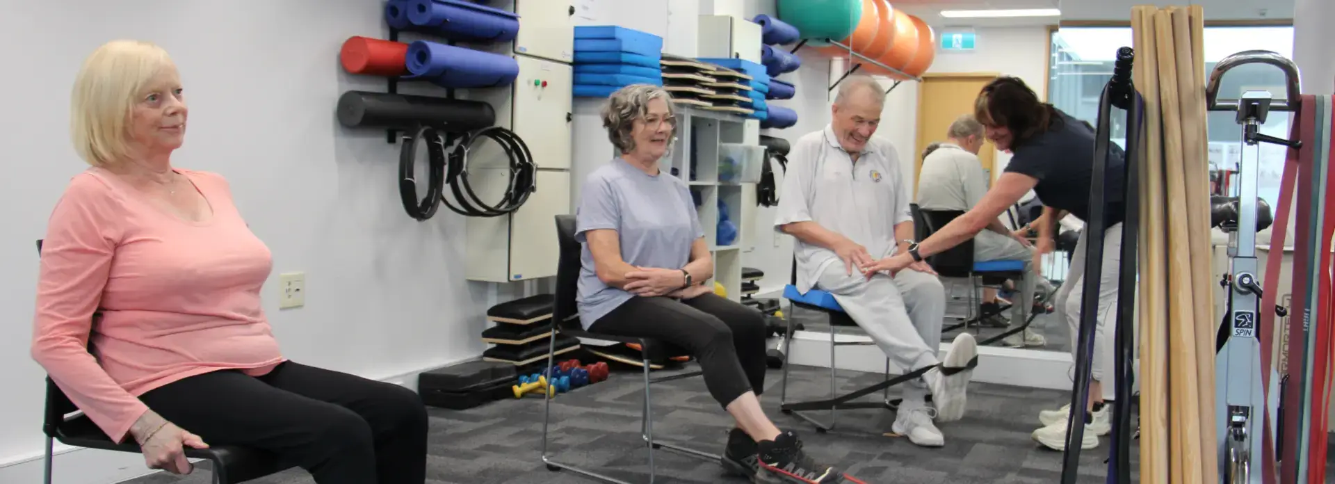 Seniors exercising with trainer in therapy gym