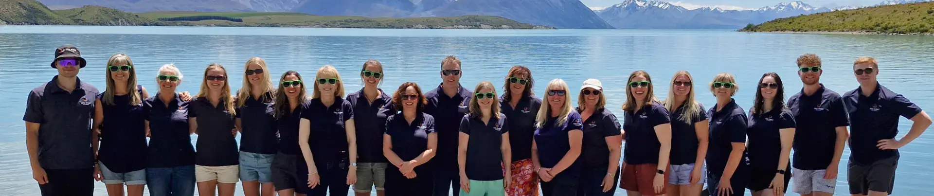 Team posing by alpine lake with mountains